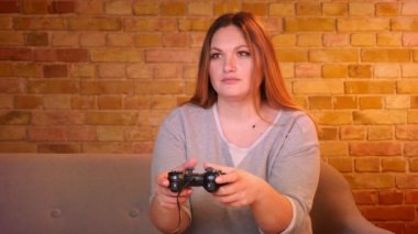 Kilolu ev hanımı joystick kullanarak video oyunu oynarken çok dikkatli olmak ve rahat evde sevk.