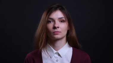 Siyah arka planda kameraya barışçıl izlerken genç esmer iş kadını Portresi.