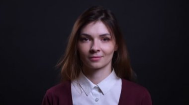 Siyah arka planda kameraya huzurlu ve güzel bir gülümseme ile izlerken genç esmer iş kadını Portresi.