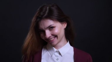 Siyah arka plan üzerinde kameraya sevinçle gülümseyen genç esmer iş kadını Portresi.