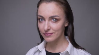 Beyaz gömlekli yetişkin çekici beyaz kadın closeup portre kamera gri izole arka plan ile mutlu bir şekilde gülümseyen bakıyor