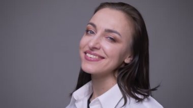 Beyaz gömlekli yetişkin çekici beyaz kadın closeup portre gülümseyerek ve gri izole arka plan ile kamera bakarak bir göz kırpma yapma