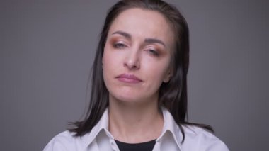 Beyaz gömlekli yetişkin çekici beyaz kadın closeup portre gri izole arka plan ile acımasız ifade ile kameraya bakıyor