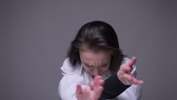 Closeup portrait of adult attractive caucasian female making crazy moves happily dancing and having fun in front of the camera with background isolated on gray — Stock Video