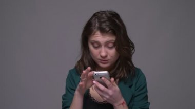 Telefonda metin yetişkin çekici esmer kadın Closeup ateş ve kamera gri izole arka plan ile gülümseyen bakarak