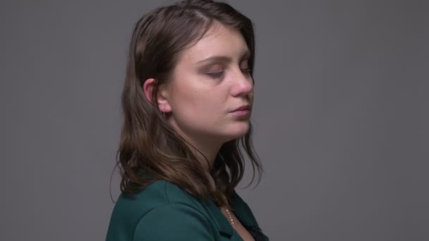 Close-up shoot van volwassen aantrekkelijke brunette vrouw draaien en kijken naar camera met achtergrond geïsoleerd op grijs — Stockvideo