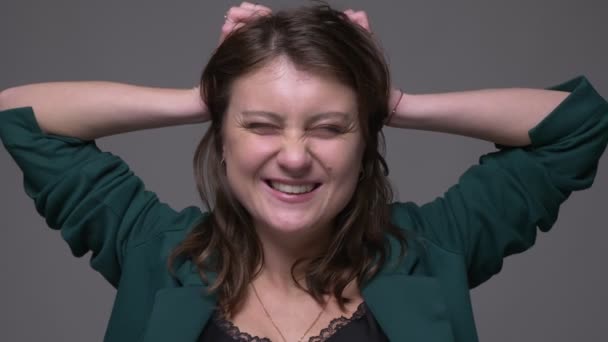 Nahaufnahme Shooting von erwachsenen attraktiven brünetten Frau aufgeregt und glücklich wirft ihr Haar Blick auf Kamera mit Hintergrund isoliert auf grau — Stockvideo