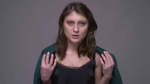 Closeup lő felnőtt vonzó barna nő csábítóan pózol a kamera előtt a kabát háttérrel izolált szürke — Stock videók