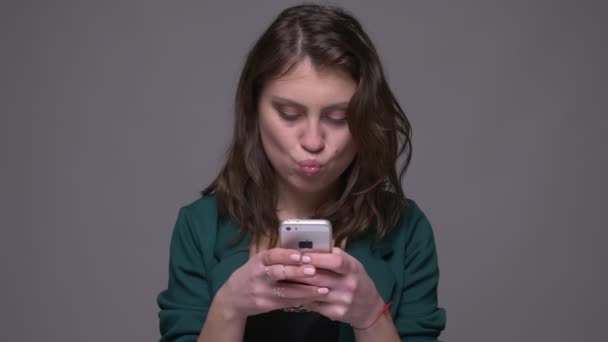 Κοντινό πλάνο του ενήλικα ελκυστικό μελαχρινή θηλυκό χρησιμοποιώντας το τηλέφωνο με φόντο απομονώνεται σε γκρι — Αρχείο Βίντεο