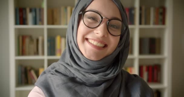 Ritratto di donna d'affari musulmana in hijab e occhiali che ridono gioiosamente nella macchina fotografica della biblioteca . — Video Stock