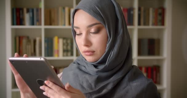 Портрет мусульманского студента в хиджабе, смотрящего на скрижаль, внимательно погруженного в работу в библиотеке . — стоковое видео