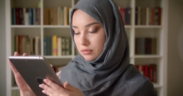 Potret profil mahasiswa muslim yang berhijab melihat ke dalam tablet yang penuh perhatian yang tenggelam dalam bekerja di perpustakaan . — Stok Video