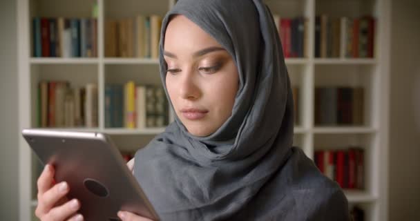 Πορτραίτο του μουσουλμανικού μαθητή σε χιτζάμπ δείχνει πράσινη οθόνη αποχρώσεων του δισκίου για να συστήσει την εφαρμογή στη βιβλιοθήκη. — Αρχείο Βίντεο