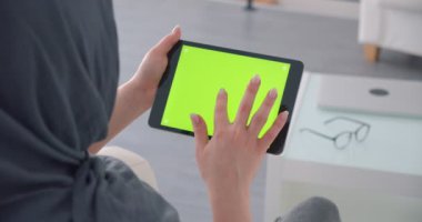 Hijab Müslüman iş kadını yeşil renk ekran ile yatay tablet uygulama açar ve özenle saatler.