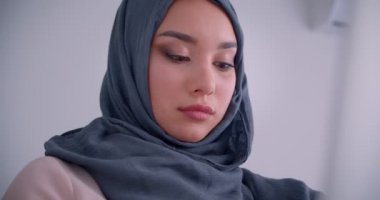 Başörtüsü takan Müslüman iş kadınının yakın çekim portresi kameranın dikkatini dağıtıyor ve sevinçle içine gülümsüyor.
