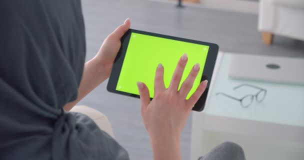 Muzułmańska businesswoman w hidżab włącza aplikację na poziomej tabletce z zielonym ekranem chrominancji i patrzy uważnie. — Wideo stockowe