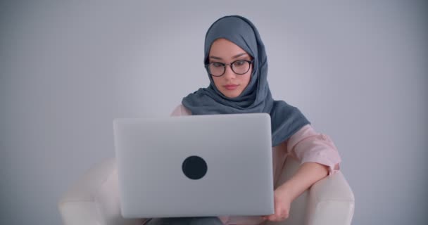 Ritratto di donna d'affari musulmana in hijab e occhiali che lavora con il computer portatile accuratamente immersa nel progetto . — Video Stock