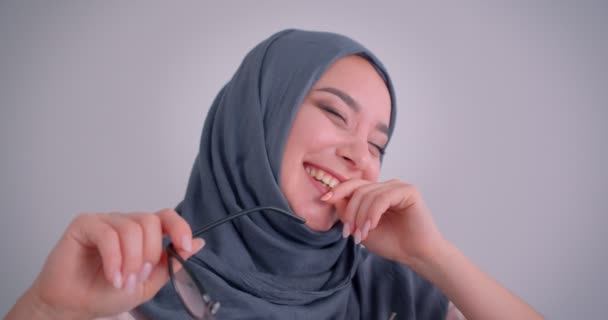 Close-up portrait of dreamy muslim businesswoman in hijab plays with her eyeglasses and laughing hardly. — Stock Video