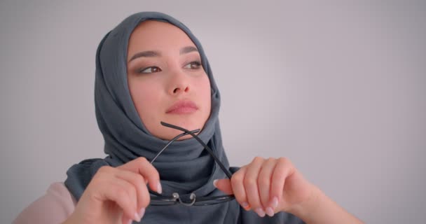 Mulher de negócios muçulmana no hijab segura seus óculos sendo imerso em pensamentos relógios calmamente na câmera . — Vídeo de Stock
