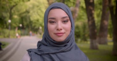 Parkta yürüyen kameraya mutlu bir şekilde ışınlanan parlak makyaj ile hijab Müslüman kadın Portresi.