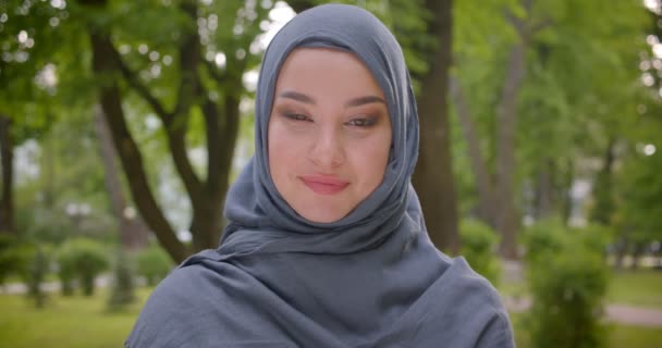 Retrato de mujer musulmana en hijab con brillante maquillaje sonríe sinceramente y deliciosamente en la cámara en el parque . — Vídeos de Stock