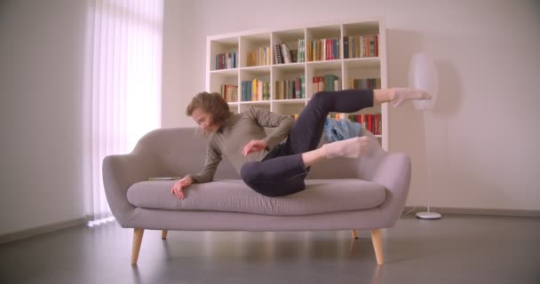 Mooie professionele danser liggend op de Bank en bewegende teder in lichte en gezellige kamer. — Stockvideo