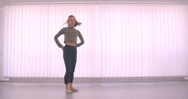 Tender caucasian professional ballerina dancing charmingly in light studio on louvers background. — Stock Video