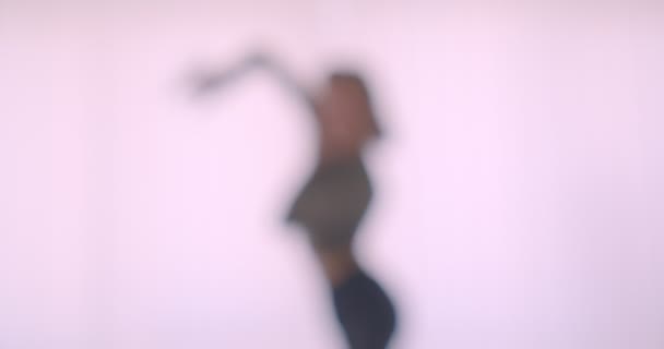 Blurred silhouette of ballerina dancing actively and professionally in white light studio. — Stock Video