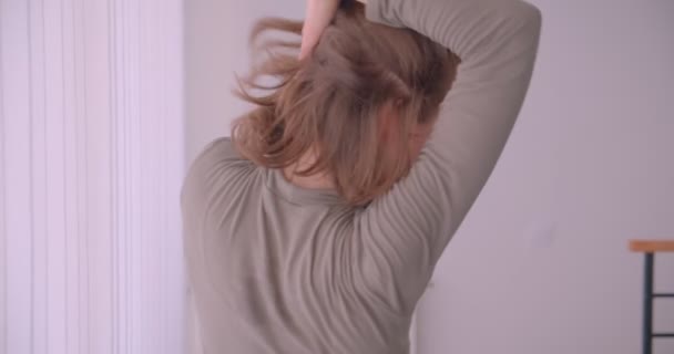 Close-up portrait of pretty professional ballerina dancing near window being calm and concentrated in light studio. — Stock Video