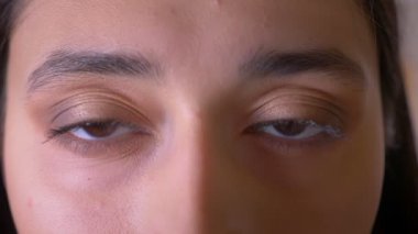 Kameraya sakince izleyen şık esmer öğrencinin yakın çekim göz portresi.