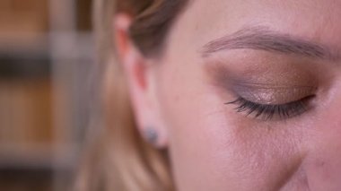 Orta yaşlı sarışın öğretmenin yakın çekim yarım yüz portresi kameraya sakince izliyor.