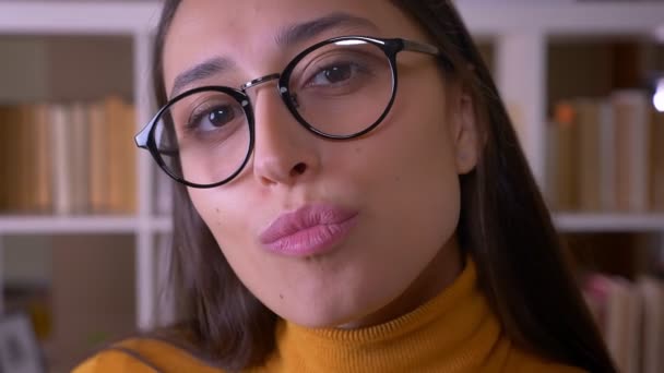 Close-up portrait of stylish brunette teacher posing smilingly into camera at the library. — Stock Video