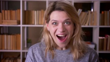 Sevimli orta yaşlı sarışın öğretmen kütüphanede son derece mutlu olmak kameraya gülüyor.