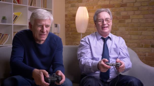 Retrato de amigos varones mayores jugando videojuegos usando joystick y consola de juegos sintiendo la sensación de aventura . — Vídeos de Stock