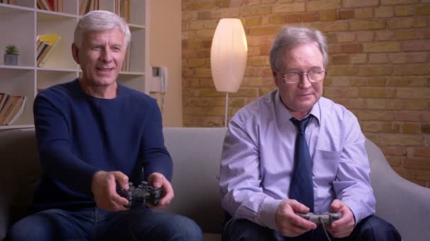 Портрет старших друзей-мужчин, играющих в видеоигры с помощью джойстика и игровой консоли, проигрывающих и выигрывающих раунд . — стоковое видео