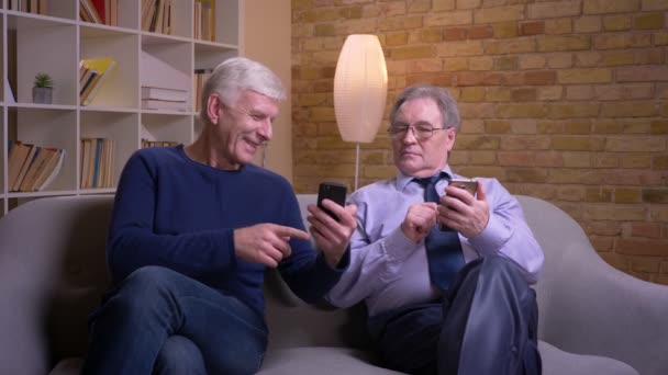 Senior homme montre smartphone à son ami et ils deviennent excités et joyeux . — Video