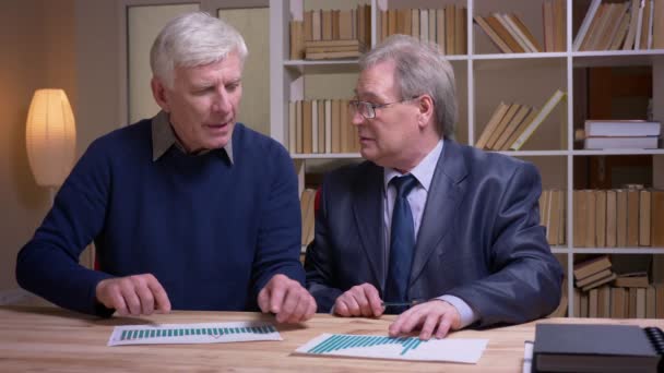 Portrait of old businessmen working together with statistic documents discussing actively the future common project. — Stock Video