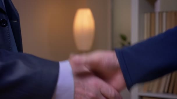 Primer plano de dos hombres de negocios con disfraces formales estrechan la mano en el fondo de la oficina . — Vídeos de Stock