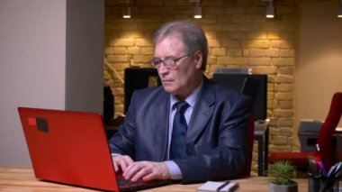 Ofiste dizüstü bilgisayar ile çalışan resmi kostüm üst düzey adam Portresi.