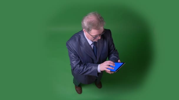 Full Höjds topp bild av Senior man slår på app och visar blå skärm av tab på grön Chromakey bakgrund. — Stockvideo