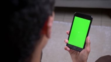 Daire içinde dikey yeşil ekranlı bir telefon tutan Hint erkek el Closeup geri görüş çekimi
