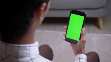 Daire içinde yeşil renk ekranlı bir telefon tutan el ile bir görüntülü görüşme olan erkek Closeup geri görüş çekimi