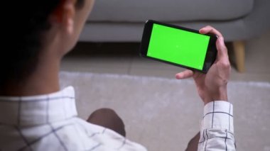 Daire içinde yeşil renk anahtar ekranı ile bir telefon tutan el ile bir görüntülü görüşme olan erkek Closeup geri görüş çekimi