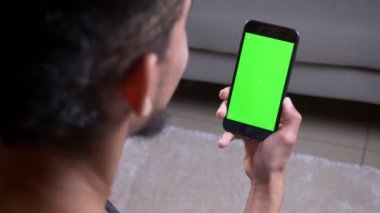 Bir video arama olan ve daire içinde yeşil ekran lı bir telefon tutarak hi sallayarak Afrikalı Amerikalı erkek Closeup geri görüş çekimi