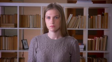 Kapalı üniversite kütüphanesinde kameraya bakan genç çekici kız öğrencinin Closeup portre