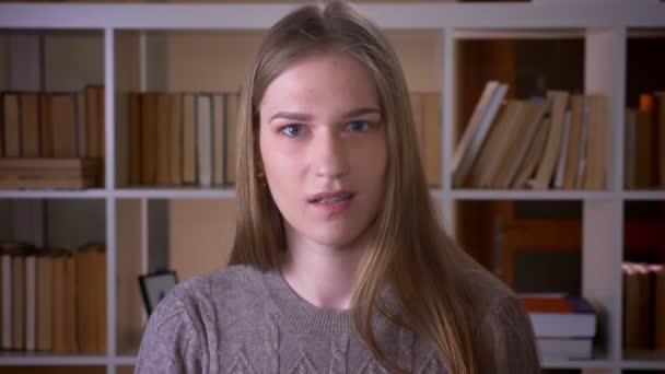 Genç çekici kız öğrencinin kapalı üniversite kütüphanesinde kameraya bakmak yok diyerek başını sallayarak Closeup portre — Stok video