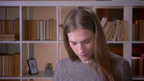 Close-up portret van jonge aantrekkelijke vrouwelijke student dansen met vreugde in de Universiteitsbibliotheek binnenshuis — Stockvideo