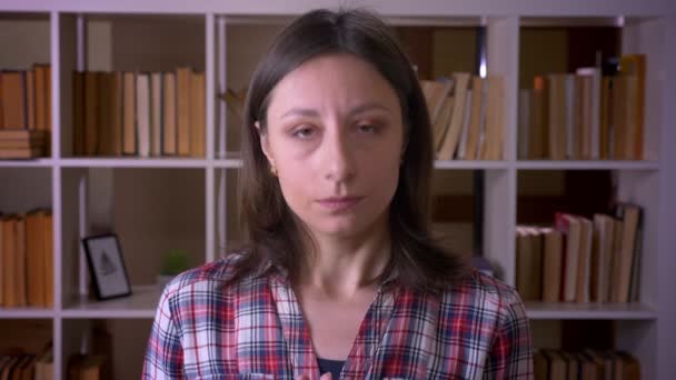 Closeup lő fiatal vonzó női hallgató bólogat mondás igen nézett kamera a könyvtárban beltéri — Stock videók