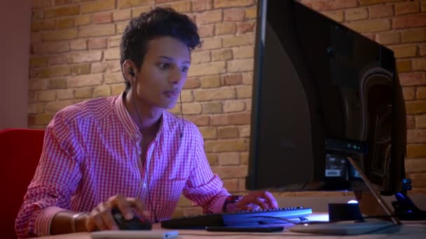 Zbliżenie strzelać młodego indyjskiego atrakcyjny mężczyzna w wibracje grając w gry wideo na komputerze niepowodzeniem i coraz sfrustrowany wewnątrz w przytulnym mieszkaniu z neonowym światłem — Wideo stockowe