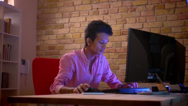 Sesión de primer plano del joven blogger masculino atractivo indio en vibraciones jugando videojuegos en la computadora y transmitiendo en vivo en el interior del acogedor apartamento con luz de neón — Vídeo de stock